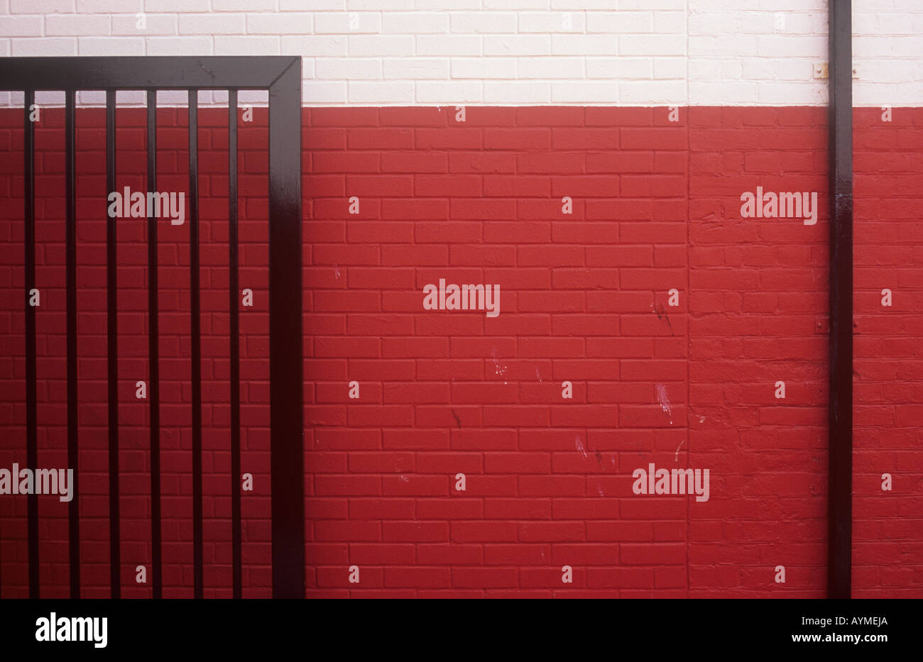 Détail de fraîchement peint rouge et crème avec brickwall black metal nouvellement peintes d'ouverture de la porte de sécurité à son égard et à l'évacuation Banque D'Images