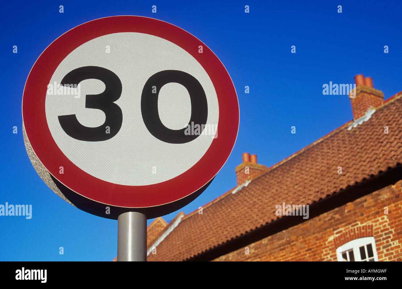 Close up de limite de vitesse circulaire panneau routier indiquant 30 contre le ciel bleu avec orange brique et sol carrelé chambre derrière Banque D'Images