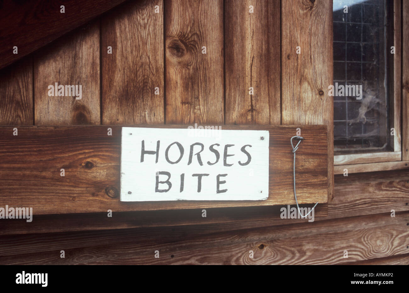 Close up de bois teinté porte stable avec crochet et fil noir peint à la main sur panneau blanc indiquant les chevaux bouchée Banque D'Images