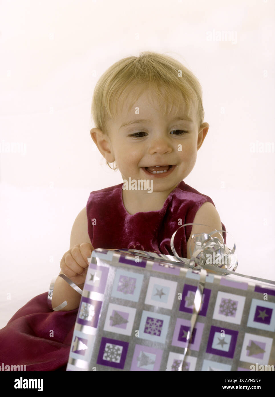 Smiling baby girl looking at a Christmas present Banque D'Images