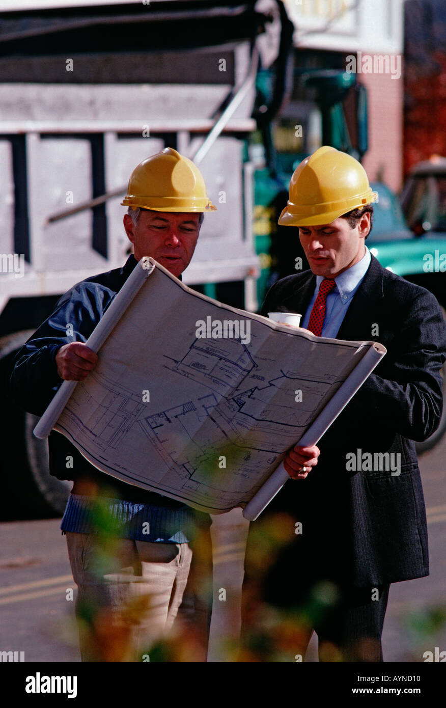 Architecte du Caucase et de construction sur le site d'emploi portant casque et looking at blueprints Banque D'Images