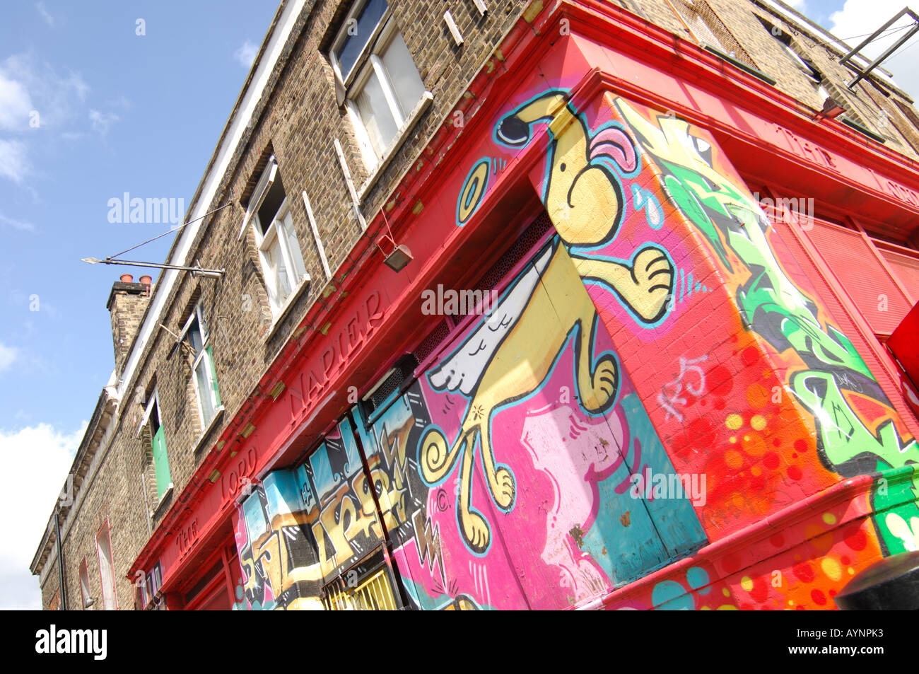 Le Graffiti d'un chien lécher le coin du bâtiment peint sur shop dans Hepscott Road, Hackney Wick, Londres Banque D'Images