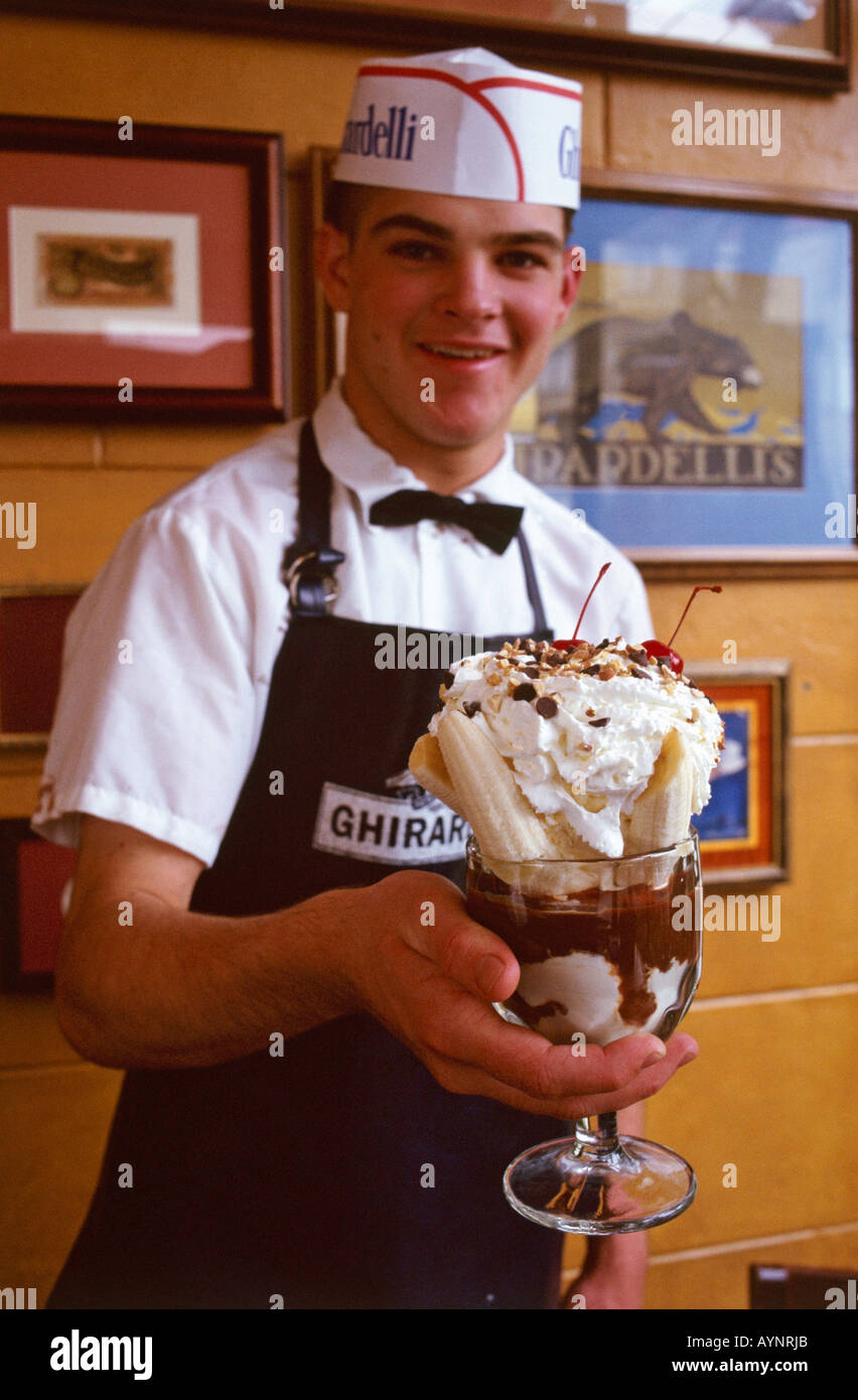 Un jeune serveur dans une smart holding uniforme de l'une de l'ice cream sundae disponible à partir de la Chocolaterie Ghirardelli à San Francisco s Ghirardelli Square complexe qui comprend l'ancien bâtiment de l'usine de chocolat Banque D'Images