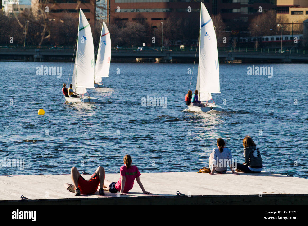Des gens assis sur un quai en regardant les voiliers dans la Charles River, Boston MA. Banque D'Images