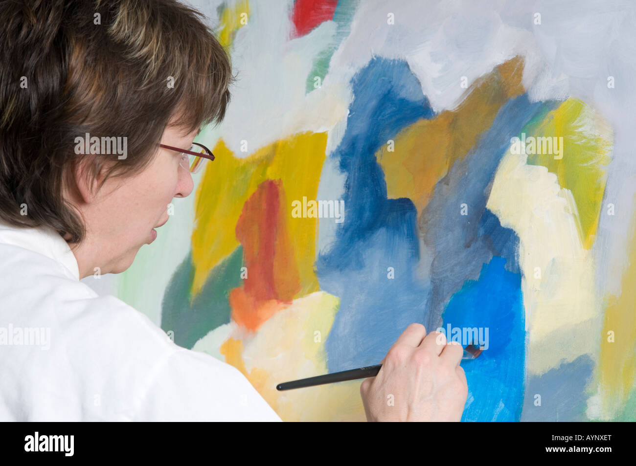 Woman painting style moderne art en studio sur toile avec smock sur Banque D'Images