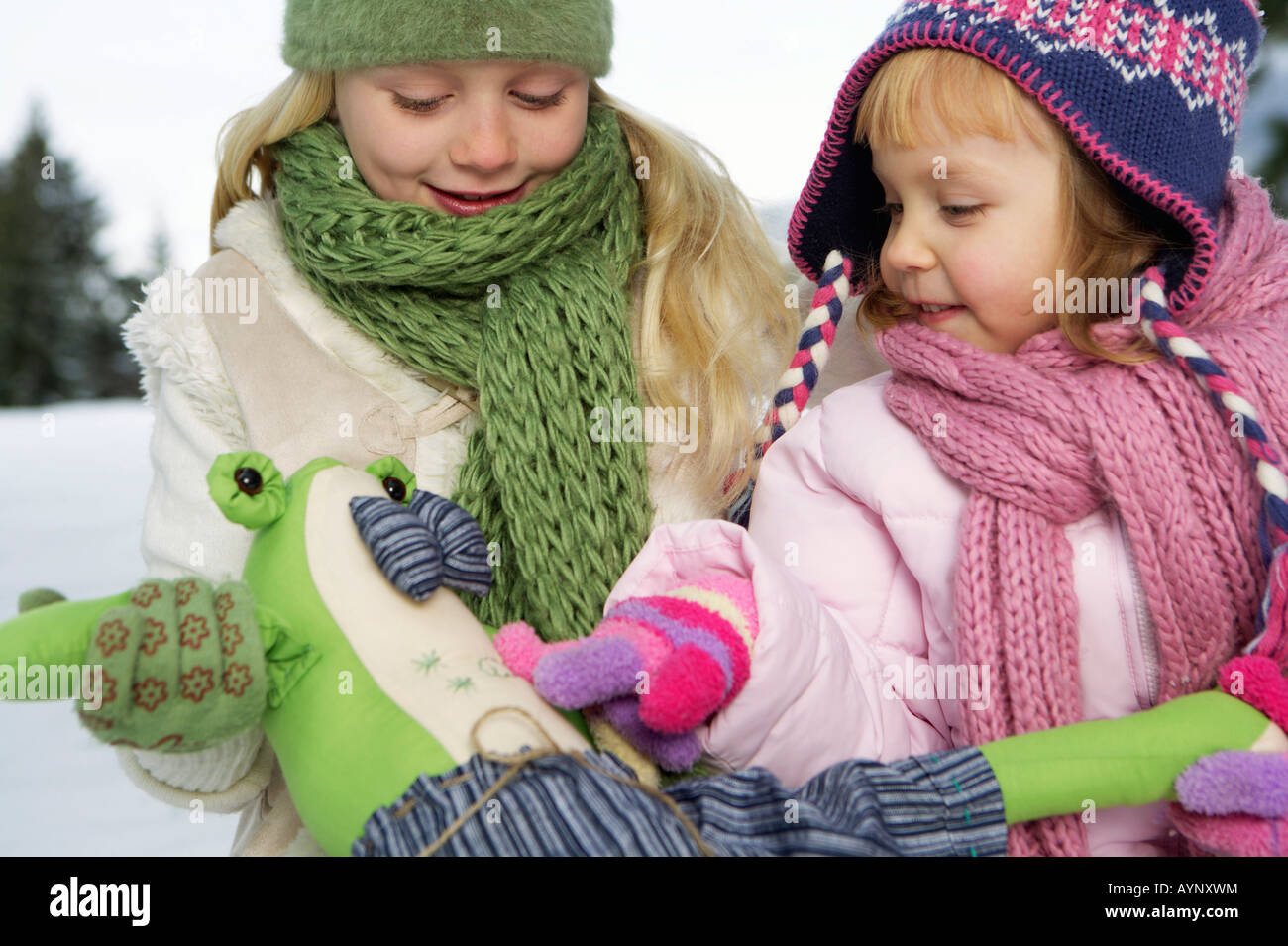 Deux filles avec un jouet animal dans la neige Banque D'Images