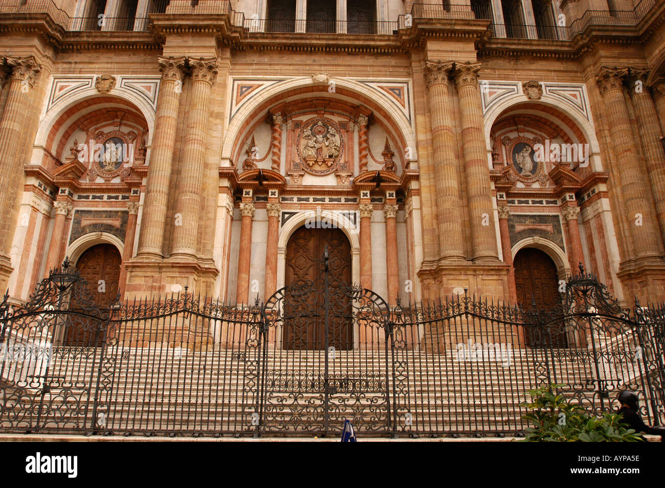 La grande façade de la cathédrale de Malaga à Malaga, Andalousie, Espagne, avec des sculptures en pierre ornées, des entrées voûtées et une clôture en fer forgé. Banque D'Images