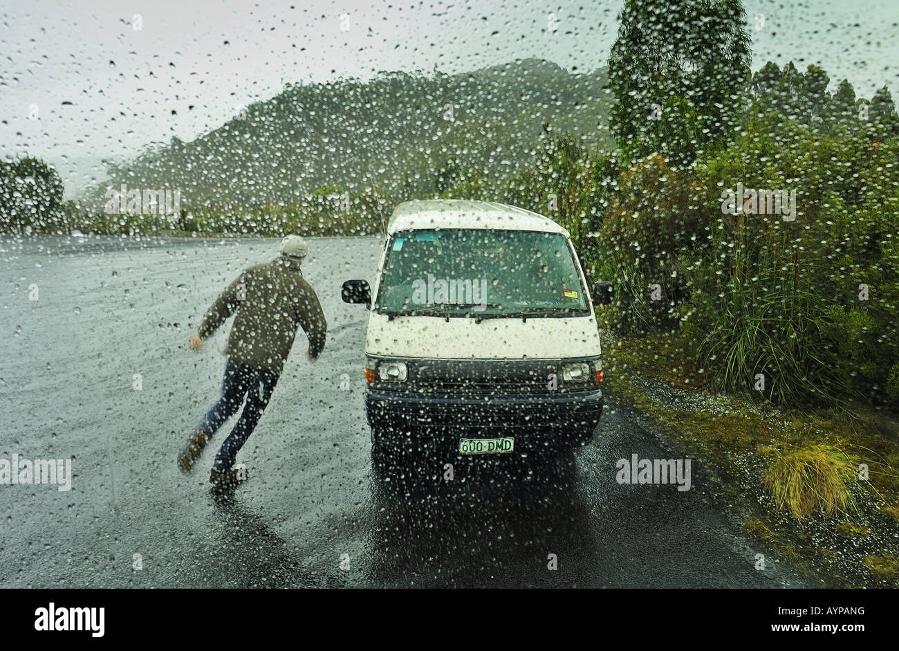 Un homme, pris dans un orage soudain, tournant pour l'abri dans sa camionnette. Vu à travers une fenêtre tachés de pluie Banque D'Images