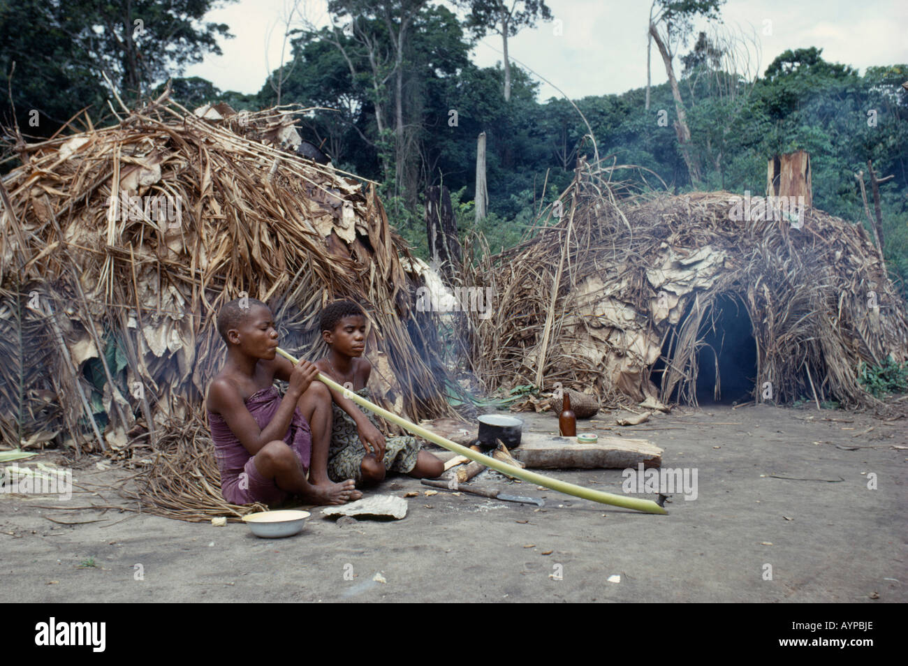 CONGO Afrique Centrale Afrique de l'Ituri Forest People femmes pygmées ethniques fumeurs de tabac de longues pipes en dehors d'un dôme de chaume huts Banque D'Images