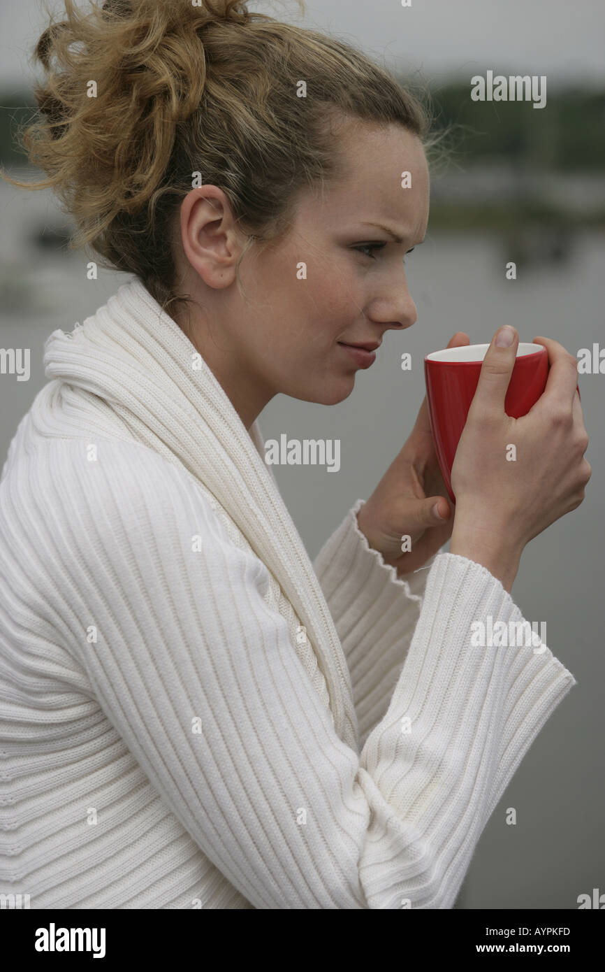Vue latérale d'un blond woman holding a mug Banque D'Images