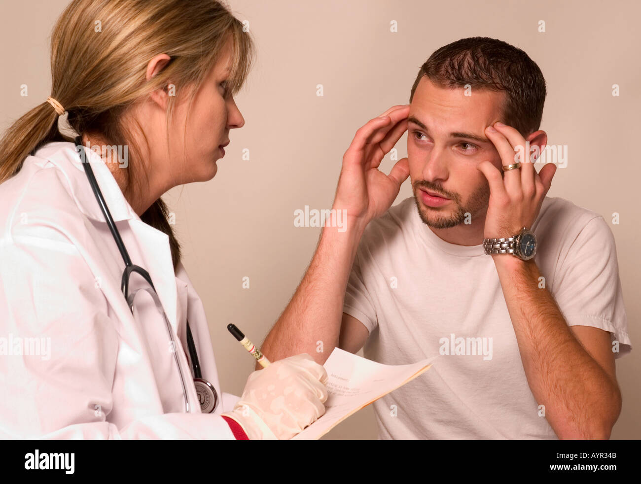Médecin généraliste féminin caucasien parle avec un patient masculin éprouvant des maux de tête lors de la consultation, États-Unis. Banque D'Images