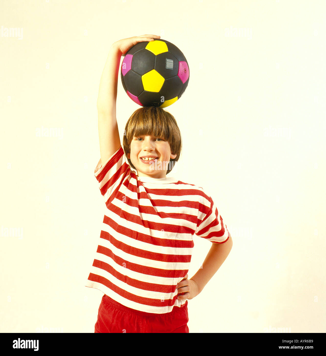 Young boy holding football au-dessus de sa tête. Photo par Willy Matheisl Banque D'Images