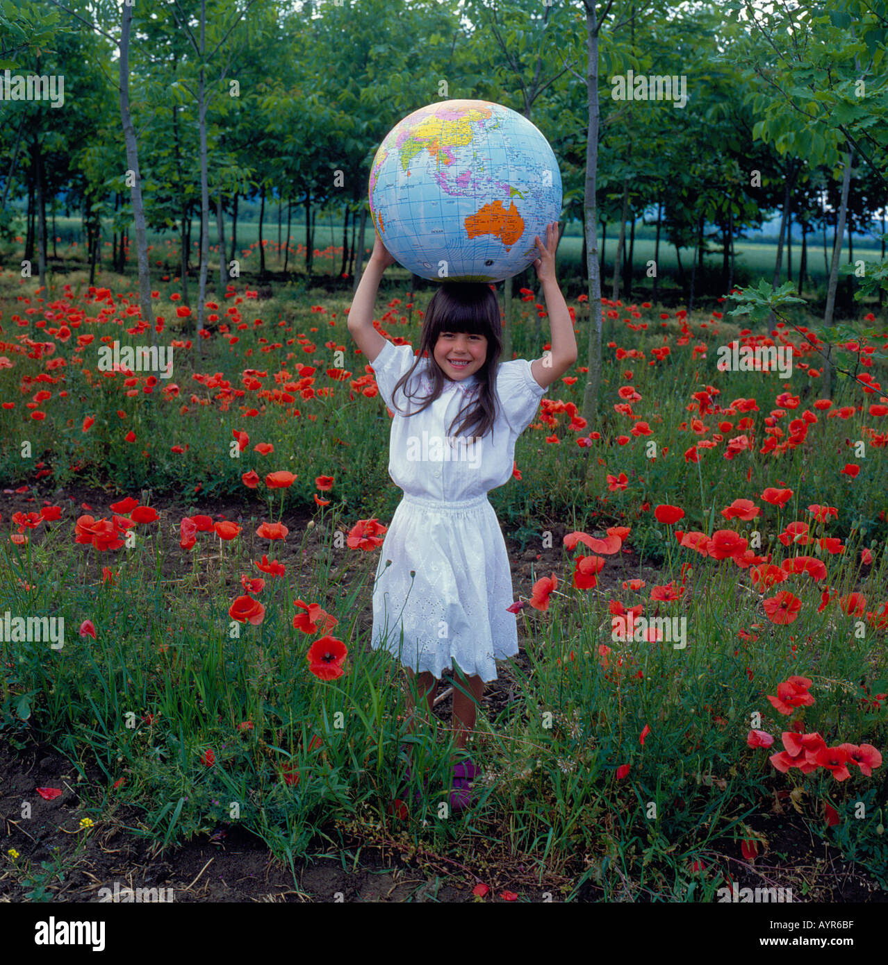 Girl standing in field holding pavot grand monde. Photo par Willy Matheisl Banque D'Images