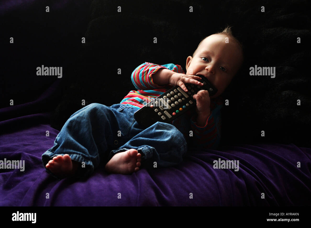 À l'âge de six mois, bébé garçon avec la télécommande sur le canapé Banque D'Images
