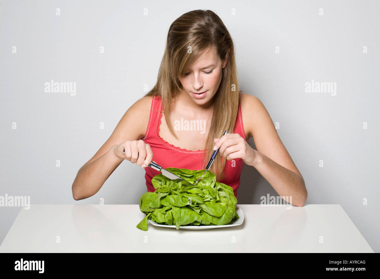 Jeune femme tenant couverts, assiette de salade verte Banque D'Images