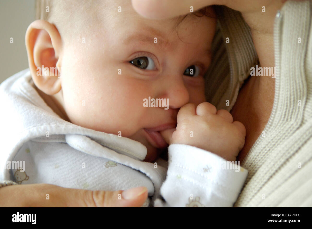 Bebe 6 Mois Sur Les Meres Arm Sucer Le Pouce Photo Stock Alamy