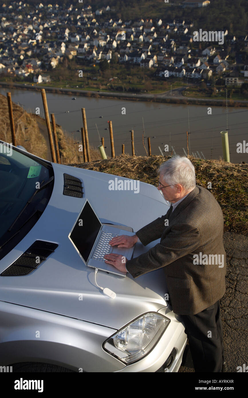 Entreprise travaillant sur un ordinateur portable sur le capot de sa voiture dans un vignoble près de Winningen, Rhénanie-Palatinat, Allemagne, Europe Banque D'Images