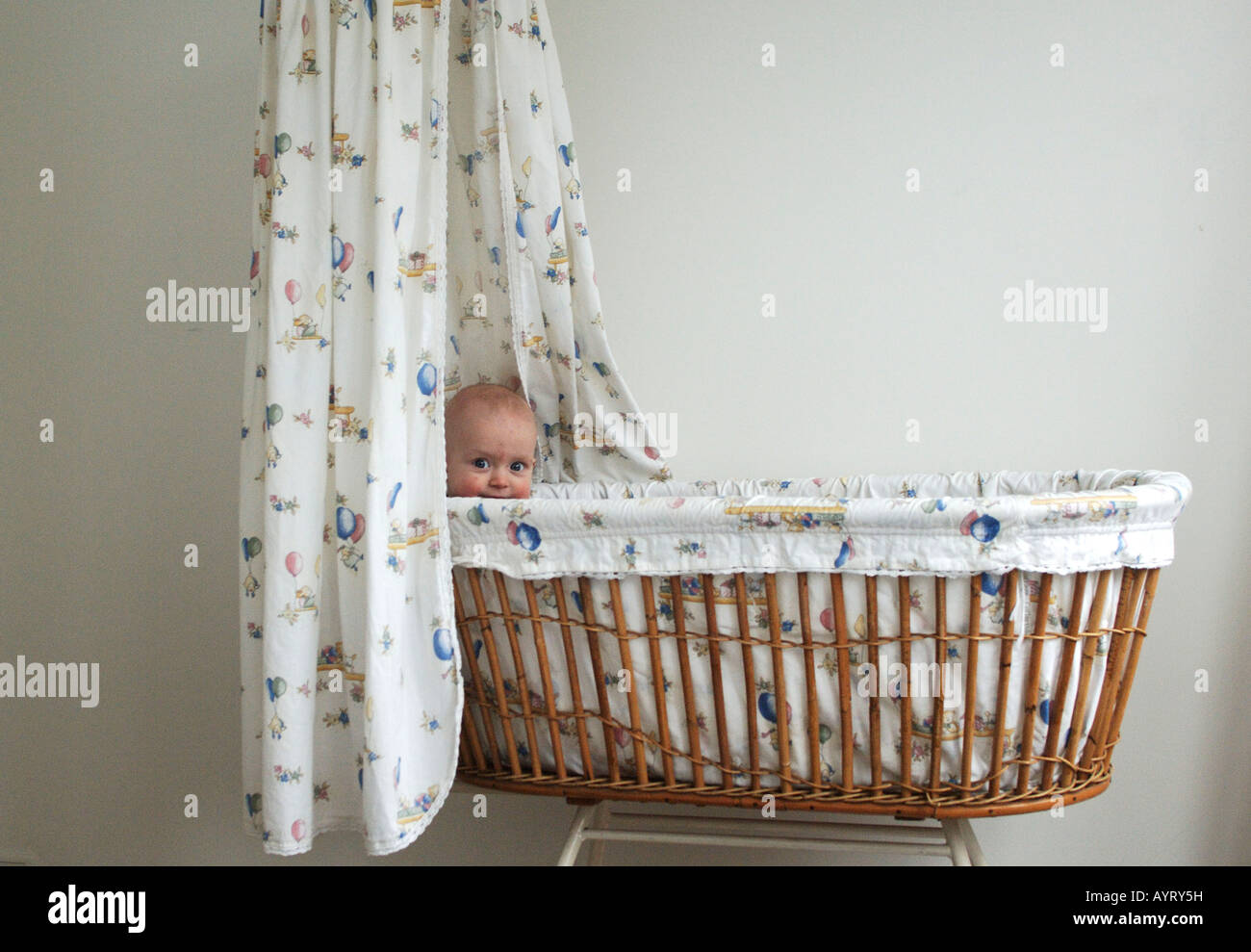 Bébé de quatre mois garçon lorgnant sur le bord de son berceau Banque D'Images