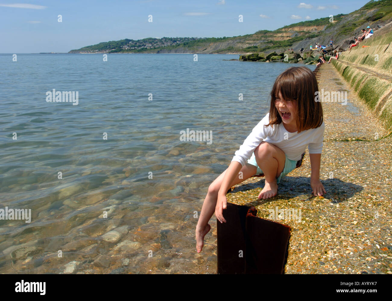 Test de l'eau, une fille dips son orteil dans l'eau à Charmouth dans Dorset UK Grande-Bretagne Banque D'Images