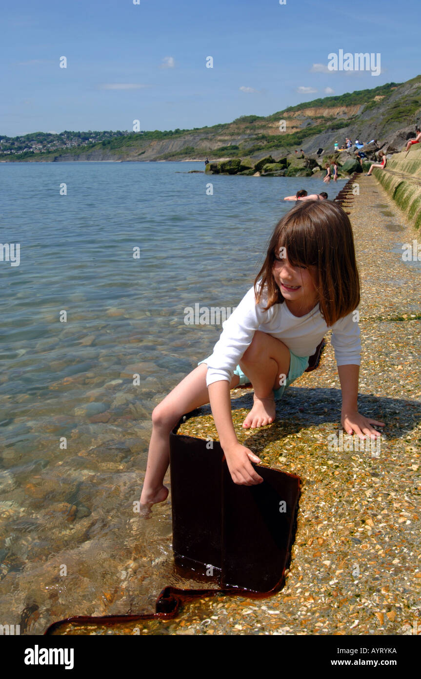 Test de l'eau, une fille dips son orteil dans l'eau à Charmouth dans Dorset UK Grande-Bretagne Banque D'Images