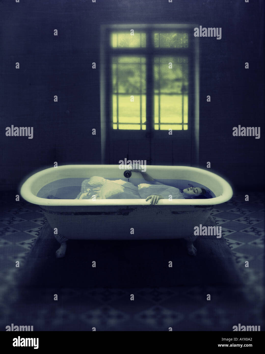 Fille en robe blanche est immergé dans l'eau dans la baignoire dans salle vide avec porte à jardin Banque D'Images