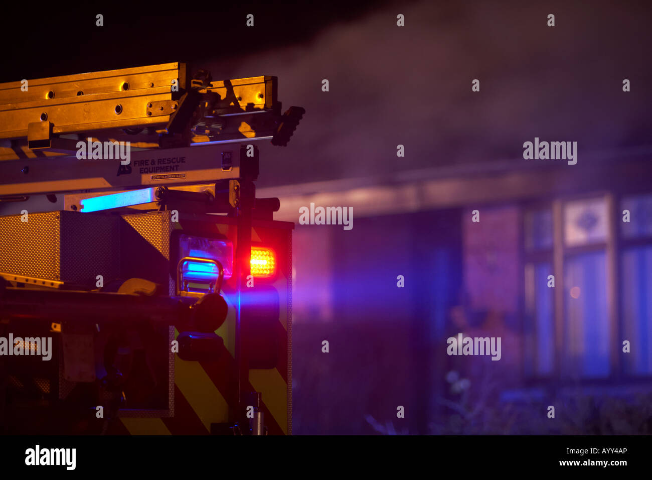 Les services d'urgence pompiers camion avec des lumières clignotantes rouges et bleus et échelle stationné à l'extérieur d'un incendie au Royaume-Uni Banque D'Images