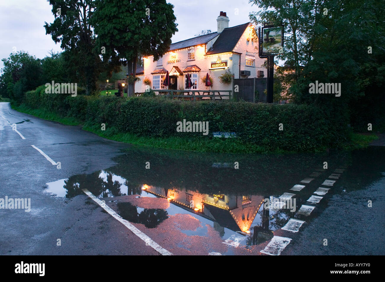 Le Brook Inn reflète dans une flaque d'eau sur la route près de Feckenham UK Worcestershire Banque D'Images