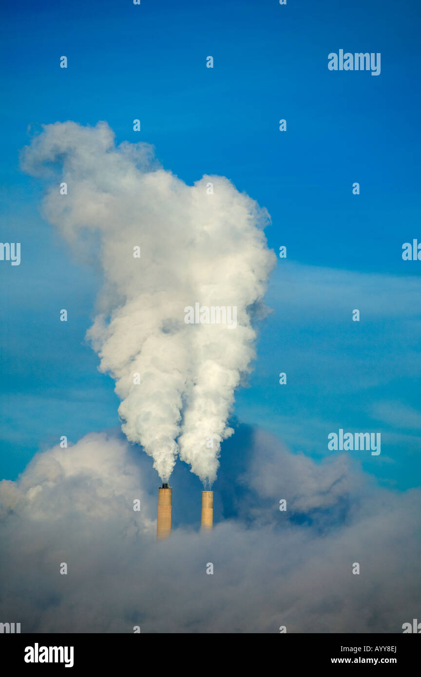 Encadrée par un brillant ciel bleu, une centrale électrique produisant de l'électricité les panaches de vapeur ou de l'envoie de la fumée dans l'air. Banque D'Images