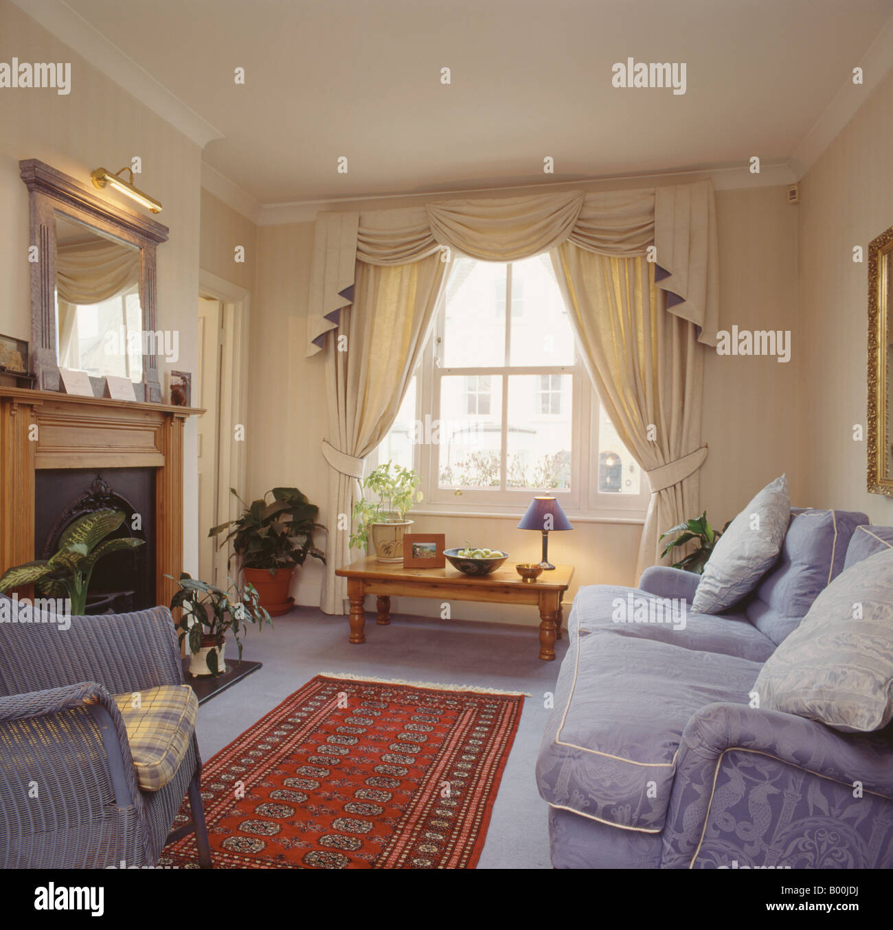 Queue Swagged et rideaux crème dans la salle de séjour avec canapé mauve et  de tapis et tapis oriental rouge Photo Stock - Alamy