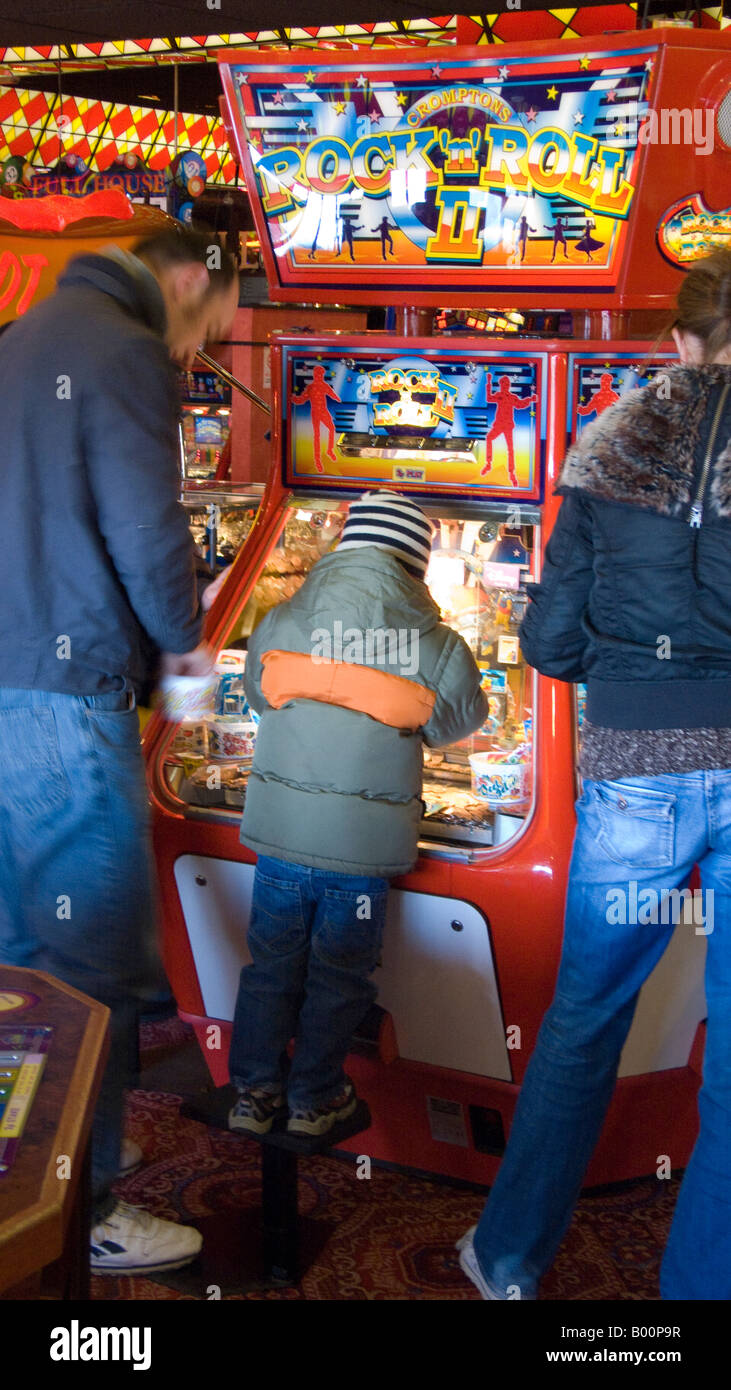 Les parents avec enfant à penny falls machine dans une salle de jeux en bord de mer Banque D'Images