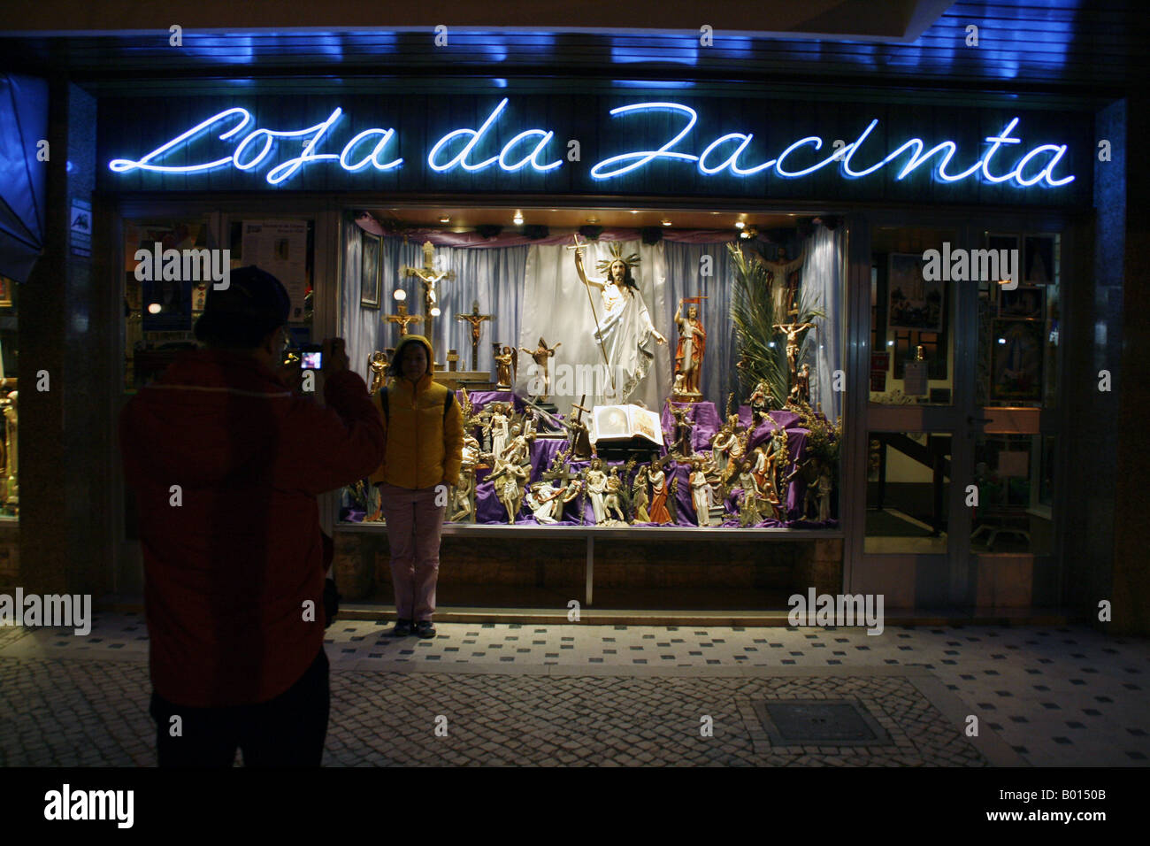 2 touristes posent devant un magasin de vente de souvenirs catholique Fatima, Portugal Banque D'Images