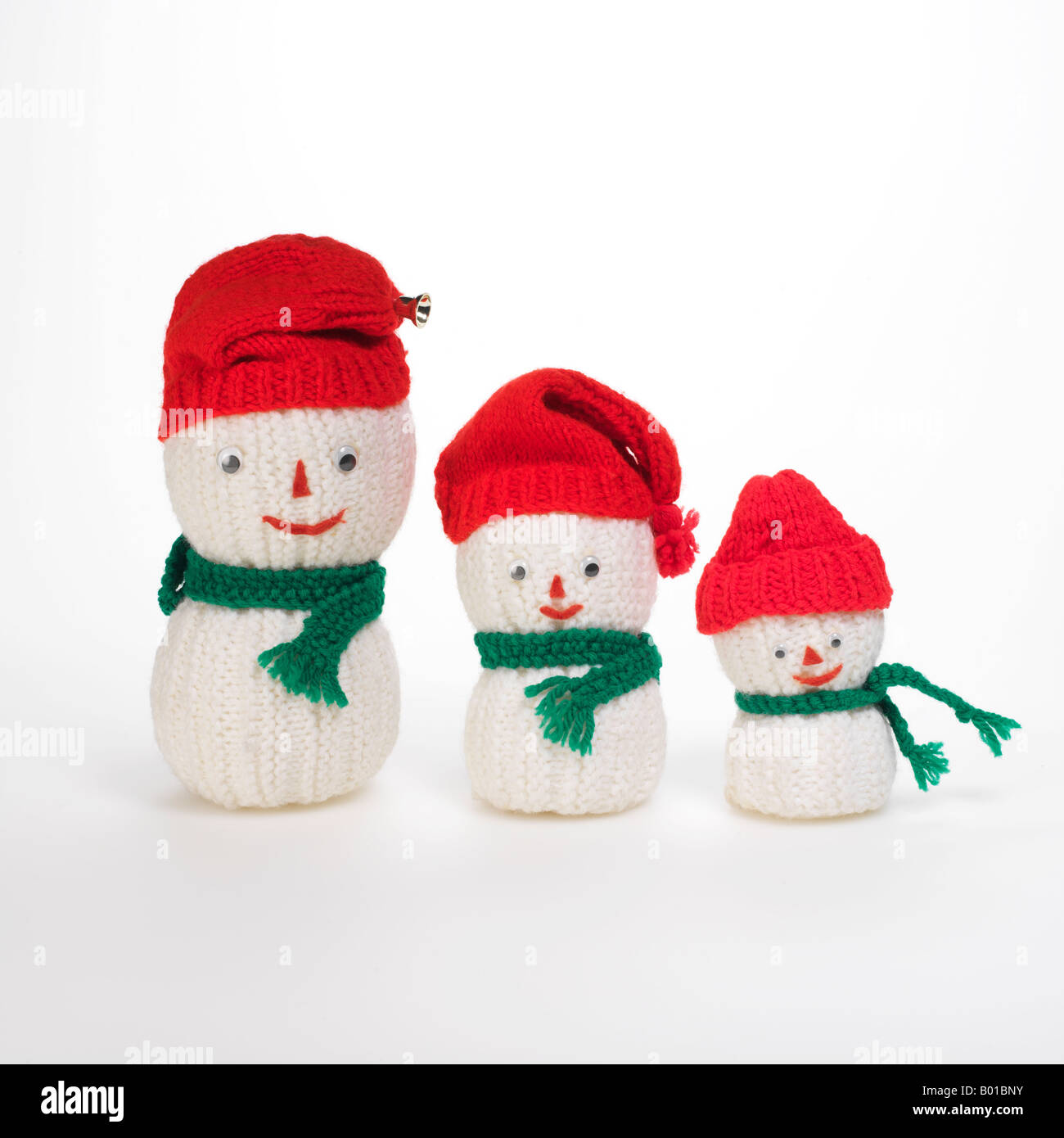 3 knit snowmen family wearing red caps et foulards vert Banque D'Images