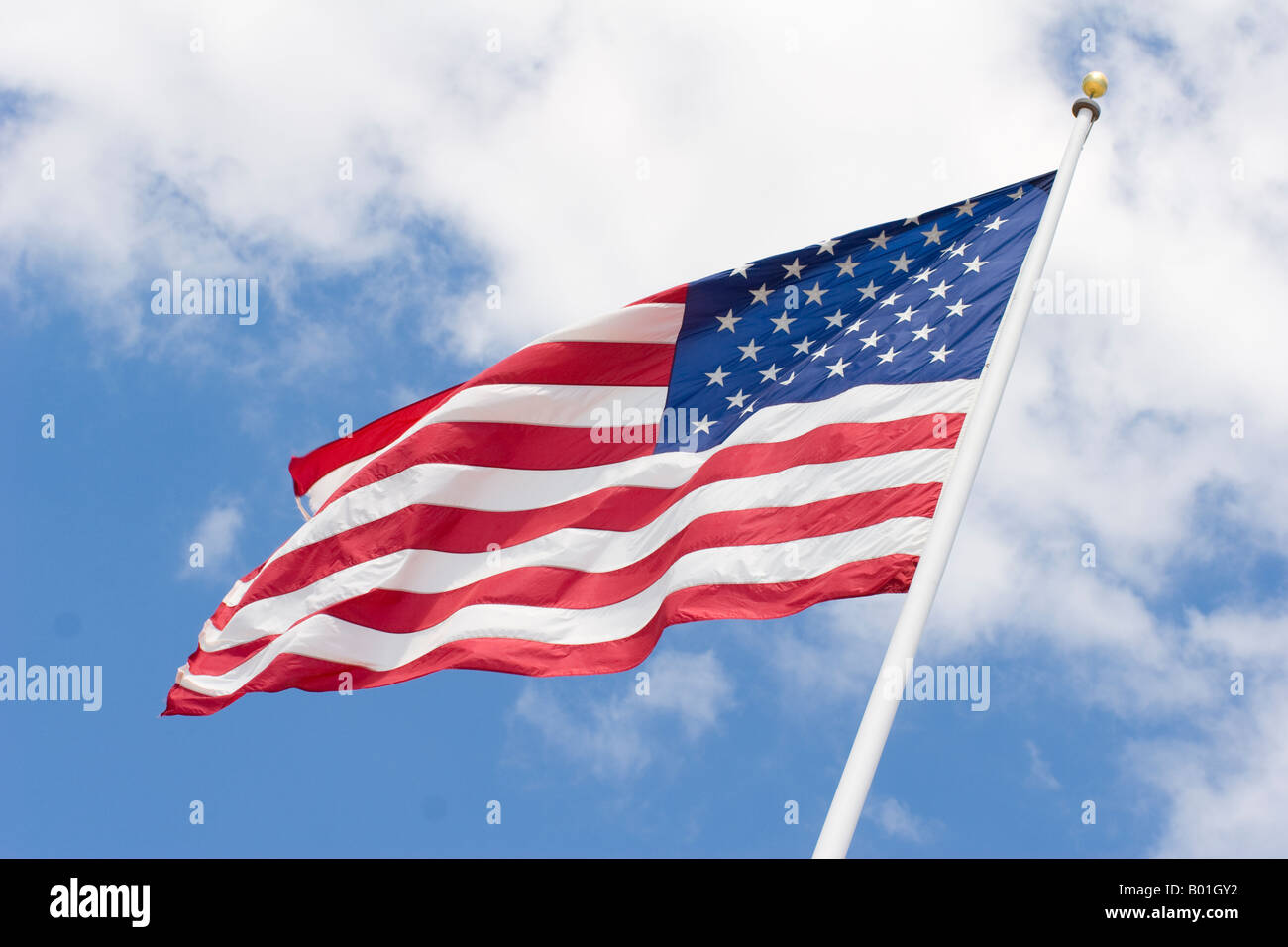 Un drapeau américain flottant au vent sur un ciel bleu avec des nuages. Banque D'Images