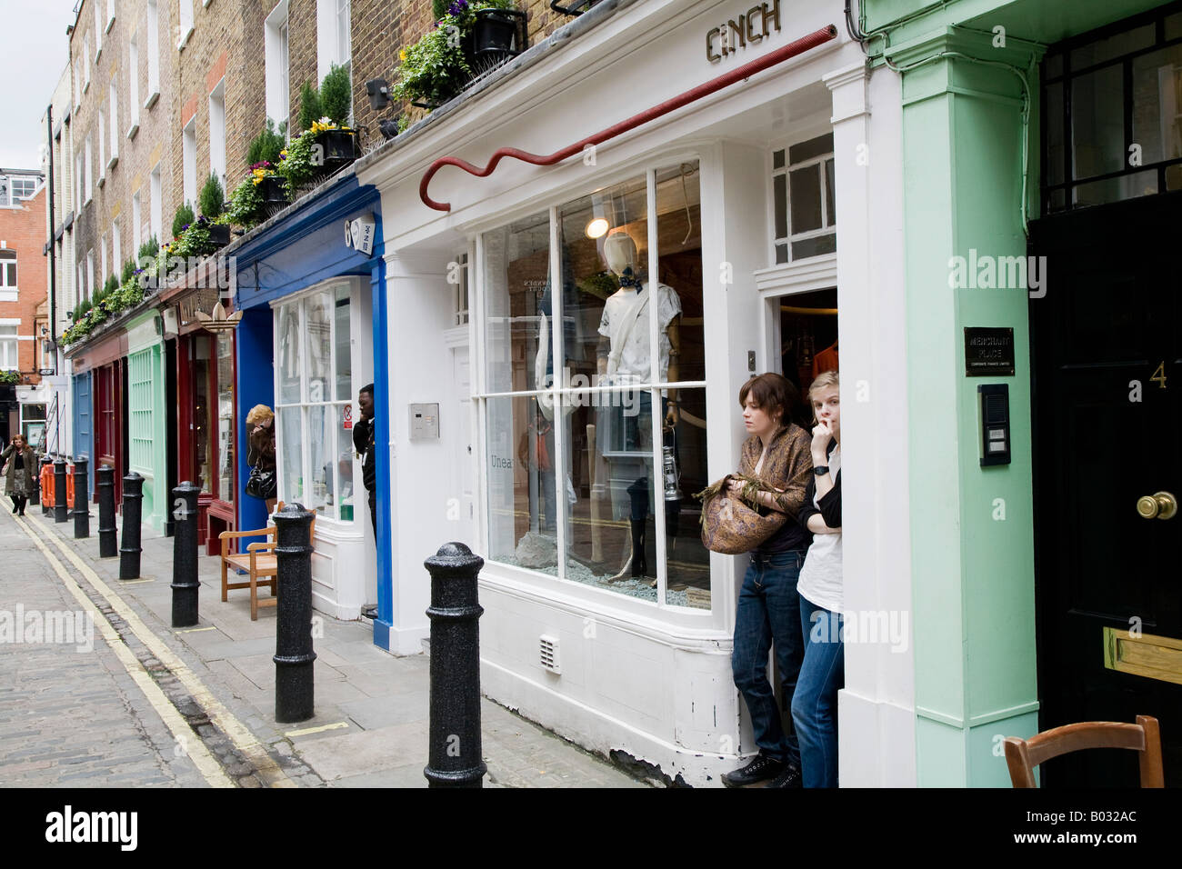 Vue vers le bas boutique rue commerçante, propriétaire debout dans l'embrasure des portes, Newburgh Street, London, UK Banque D'Images