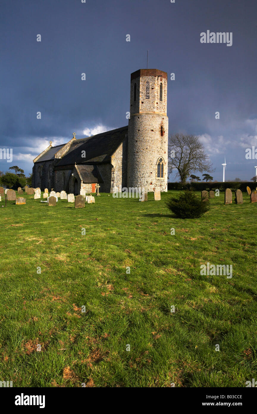 Église à Winterton sur mer avec les éoliennes modernes dans la distance sur un jour de tempête dans le Norfolk. Banque D'Images