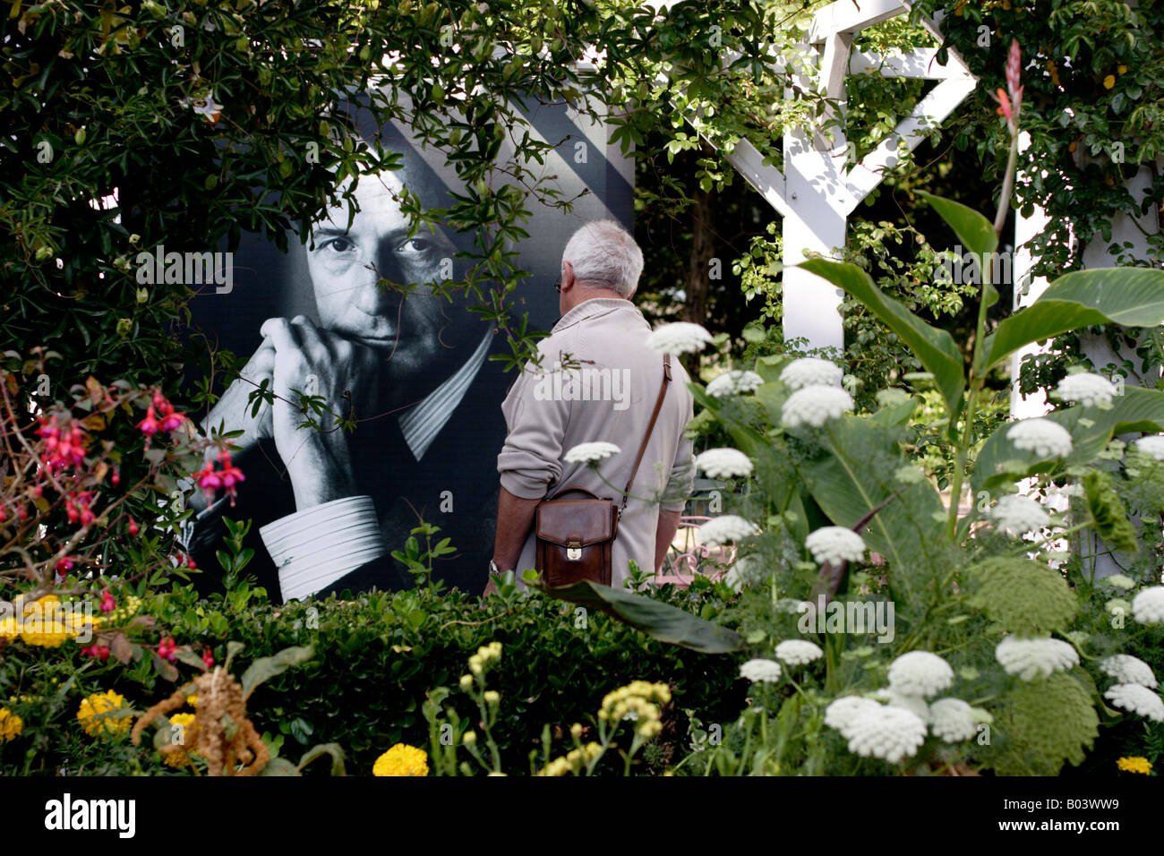 Un visiteur l'inspection d'un portrait monochrome de Christian Dior dans les jardins du Musée Dior à Granville La Manche Normandie Banque D'Images