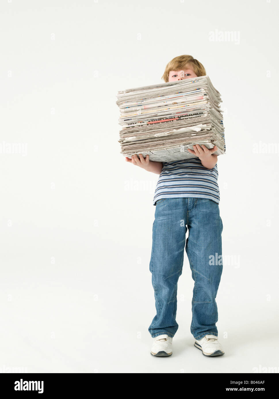 Boy holding une pile de journaux Banque D'Images