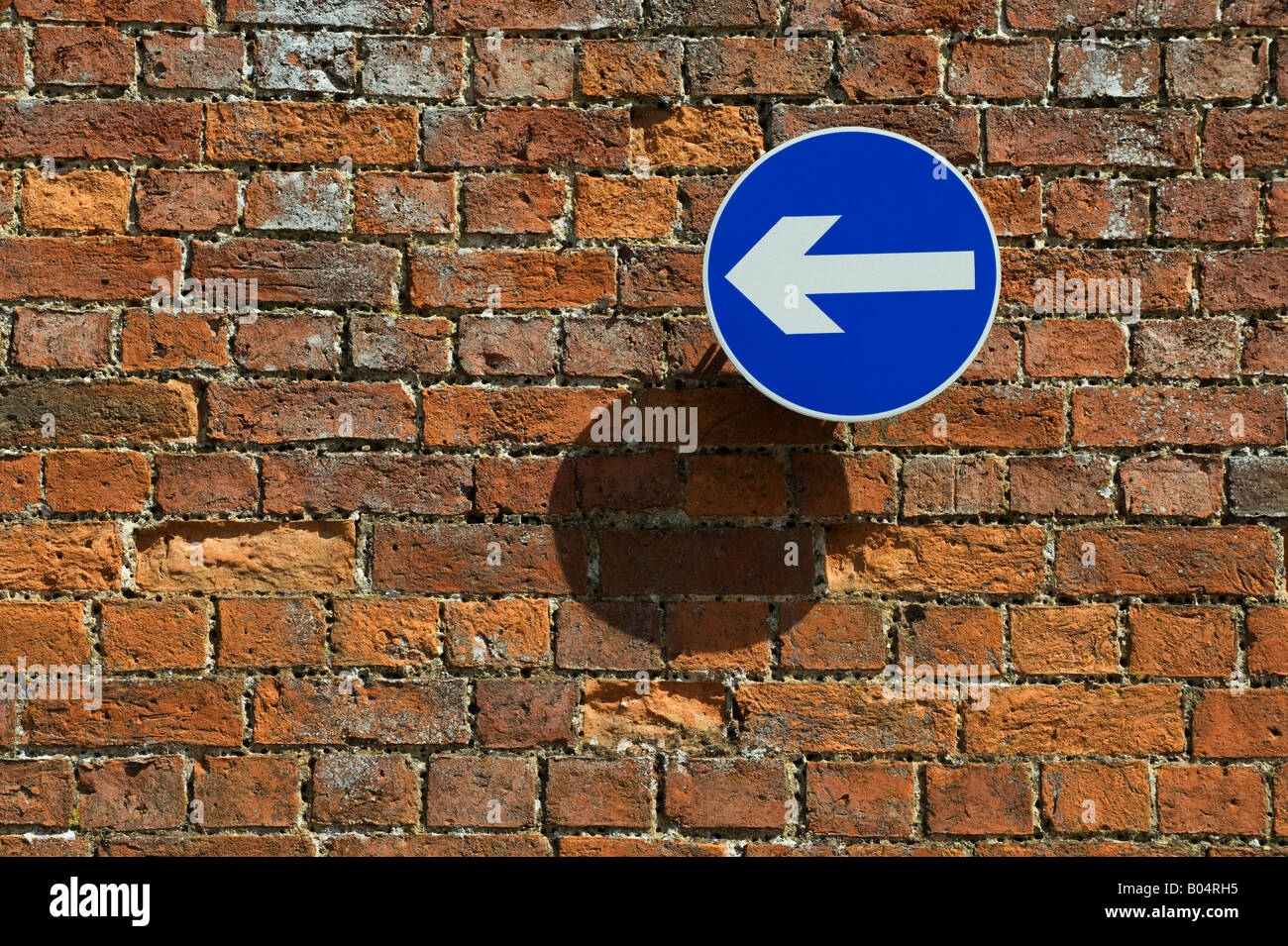 Le sens de la flèche bleu signe sur un vieux mur de briques. UK Banque D'Images