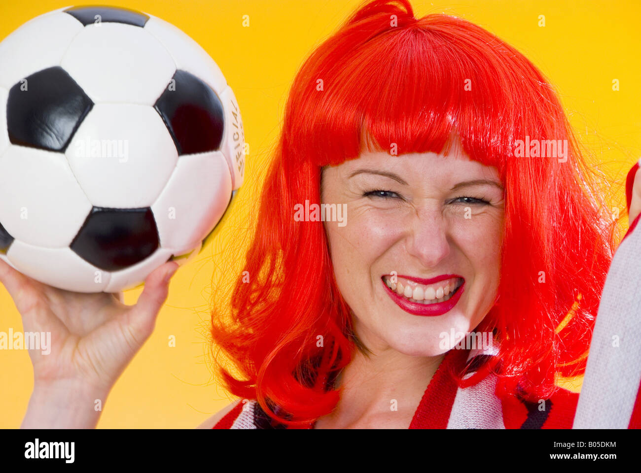 Femme enthousiaste avec le football et la perruque rouge Banque D'Images