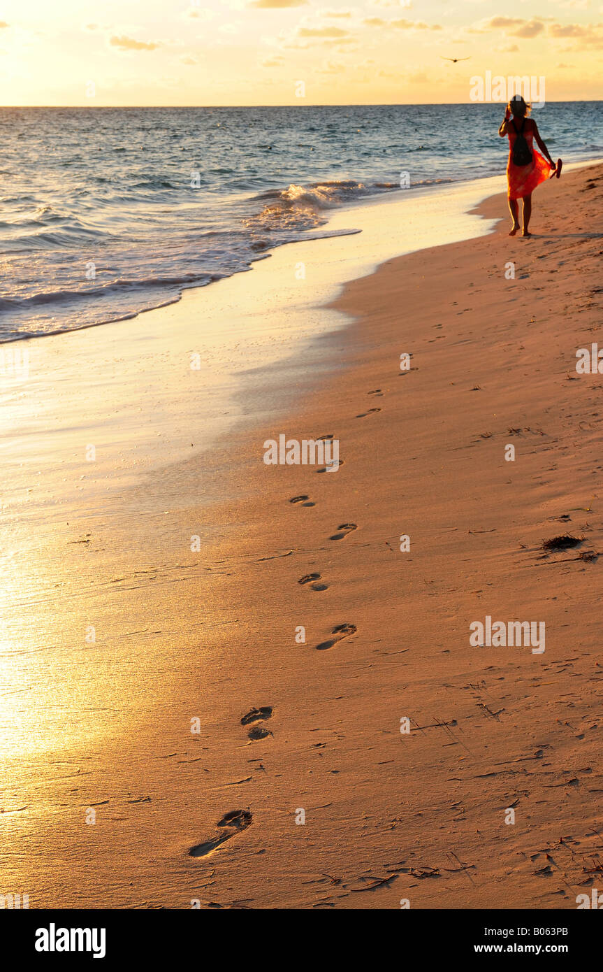 Woman walking on tropical beach at sunrise Banque D'Images