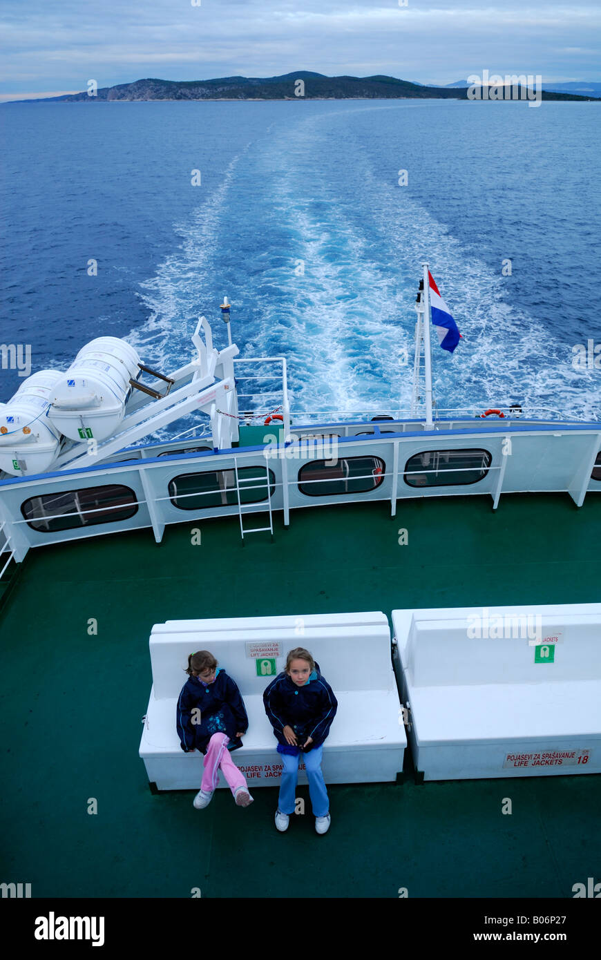 Deux enfants assis à l'arrière du ferry inter-îles à l'aube, mer et îles visibles. En route vers Dubrovnik. La Croatie Banque D'Images