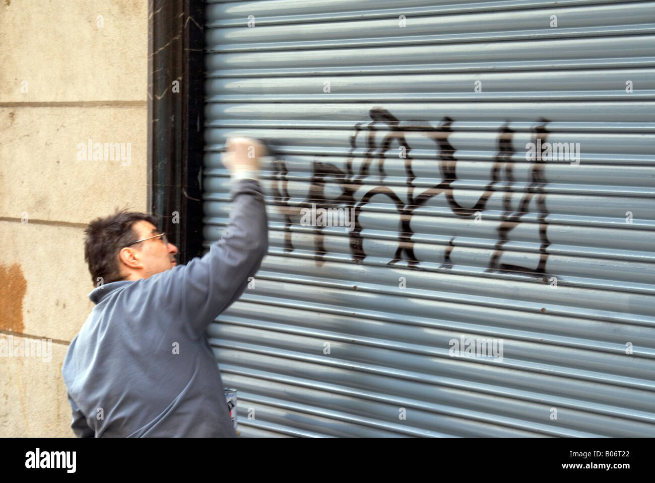 Propriétaire de boutique peindre un graffiti sur boutique de volets. Barcelone Espagne. Banque D'Images