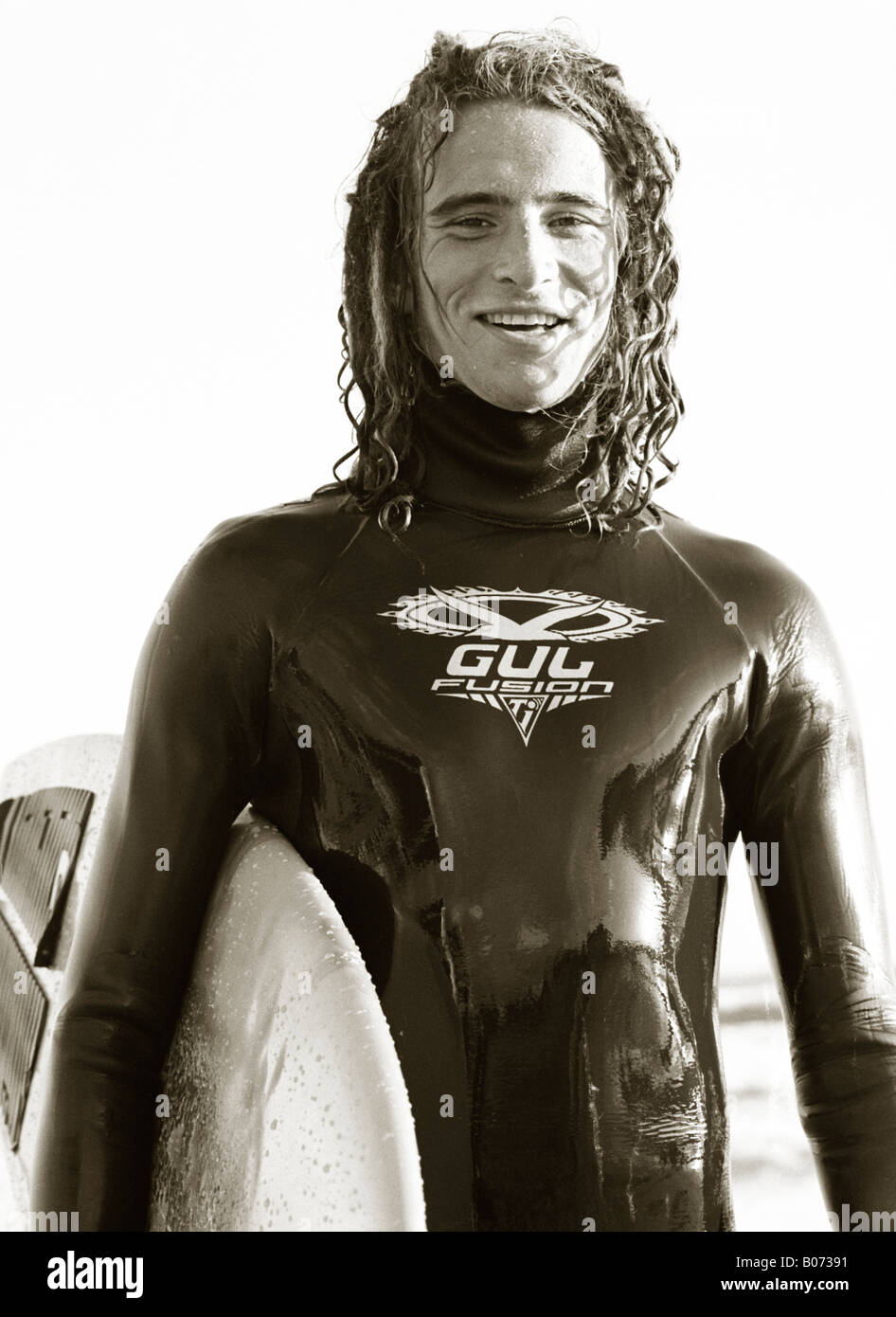 Un noir et blanc portrait of male surfer avec sa planche de surf sous le bras. Banque D'Images