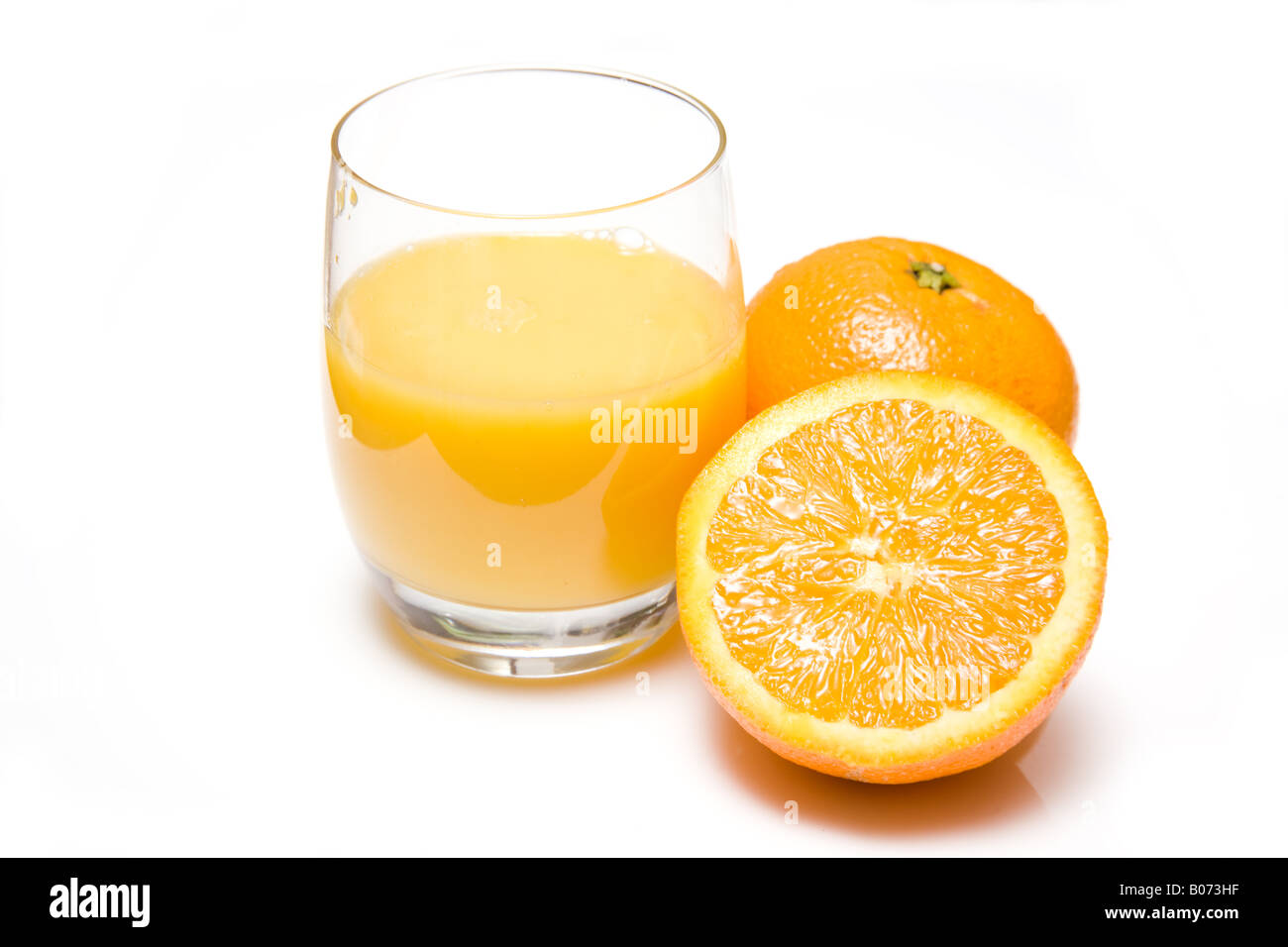 Verre de jus d'orange fraîchement pressé avec une moitié d'orange, isolated on a white background studio. Banque D'Images