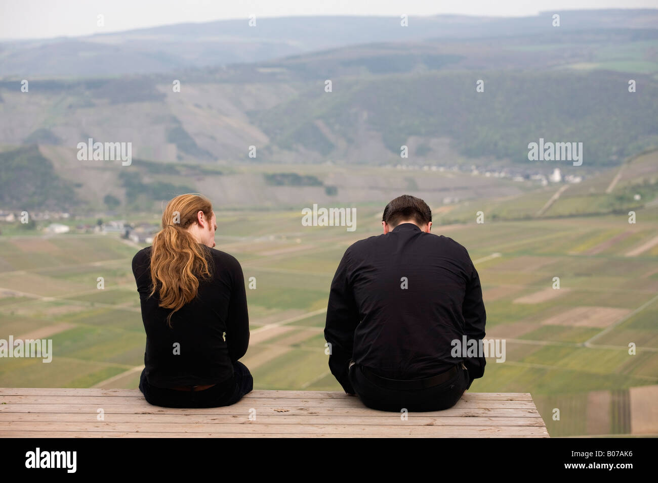 Les hommes en noir assise sur le bord d'une plate-forme en bois avec vue sur les champs bien en dessous Banque D'Images