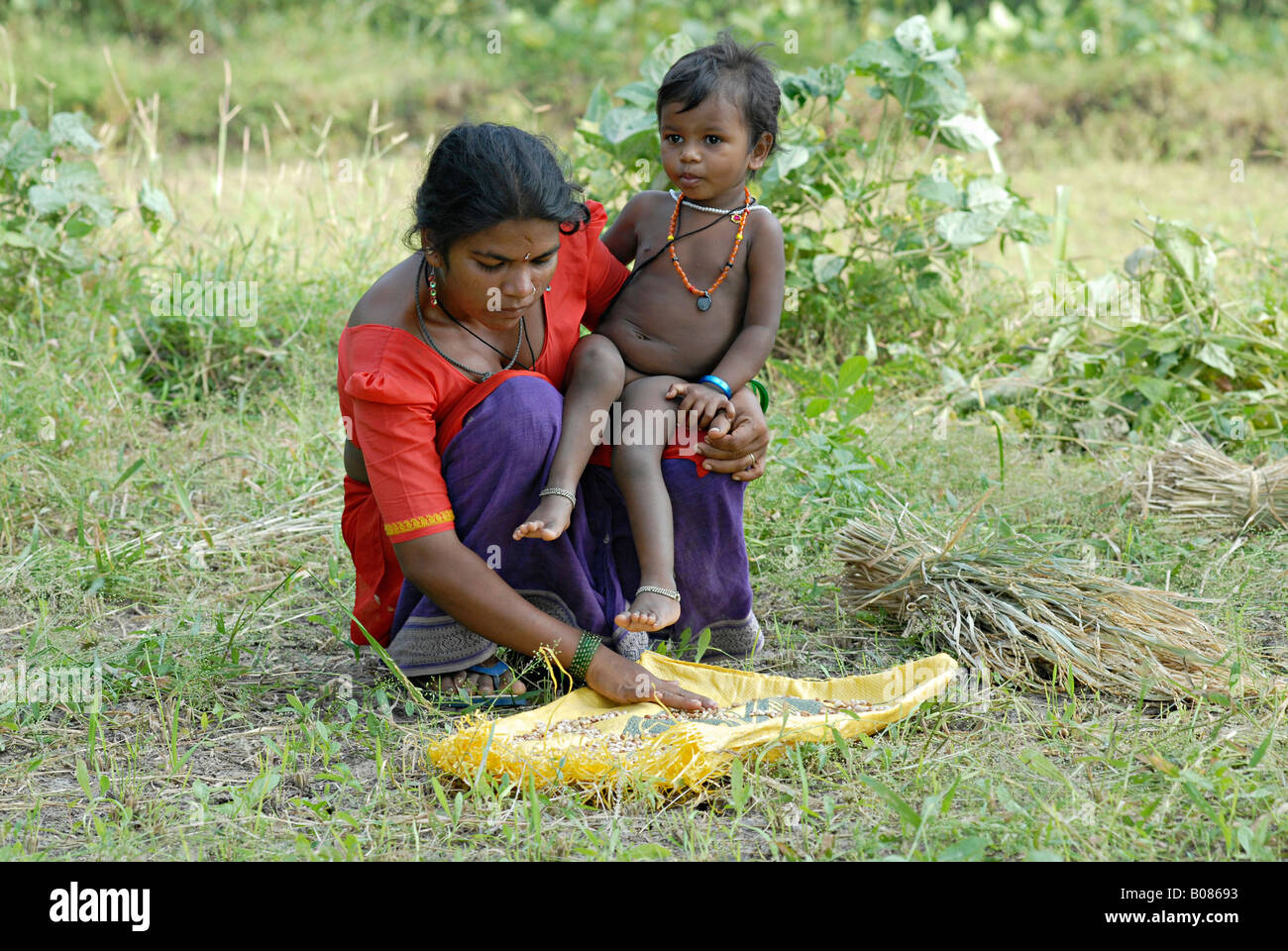 Une mère Warli céréales tri avec son enfant Banque D'Images