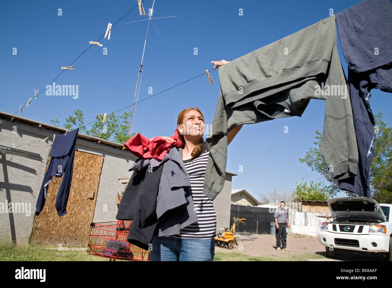 Femme hispanique prend des vêtements secs à partir de la corde à linge Banque D'Images