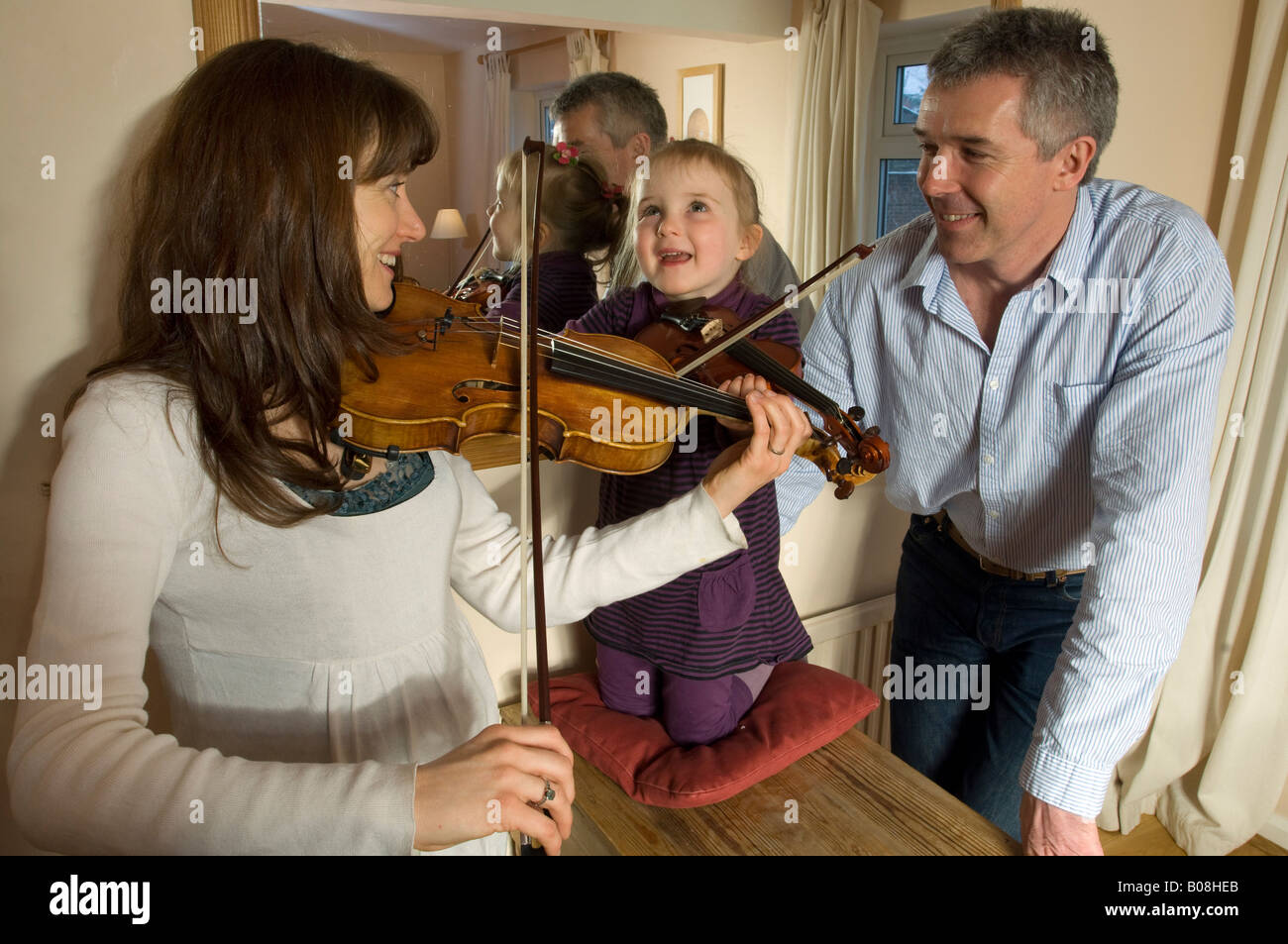 Mère et fille d'un petit violon pratique comme père regarde fièrement. Banque D'Images