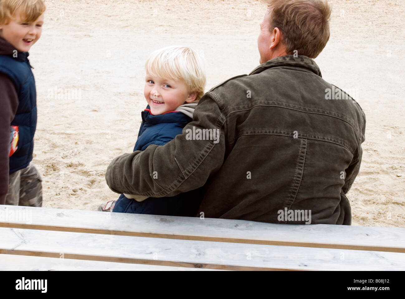 Un père aimant est assis avec ses deux fils alors qu'ils en faire ensemble durant une journée à la plage Banque D'Images
