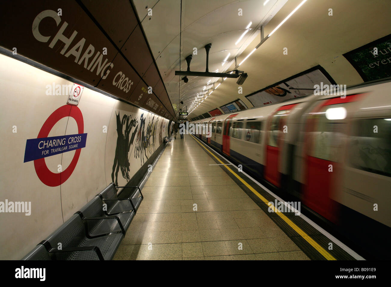 À l'intérieur de la station de métro Charing Cross, London Underground logo et train qui passe, London, England, UK Banque D'Images